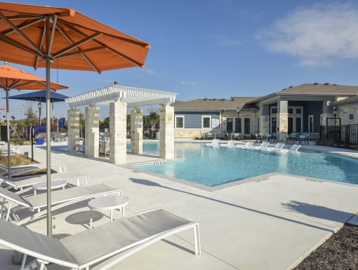 Resort-style swimming pool with in-water lounge chairs, shaded pergola seating, and a beautifully designed outdoor space.
