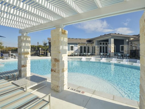 Spacious pool deck with in-water loungers, covered pergola seating, and a well-designed resort-style amenity area.