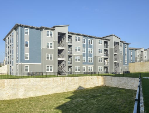 Modern apartment building exterior with clean architectural lines, private balconies, and open green space.
