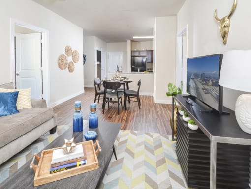 Open-concept living and dining area with wood-style flooring, modern décor, and a seamless view into the kitchen.