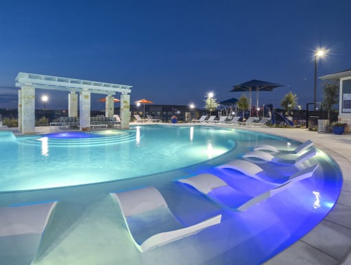 Resort-style pool with in-water lounge chairs, shaded pergola seating, and a beautifully designed outdoor lounge area.