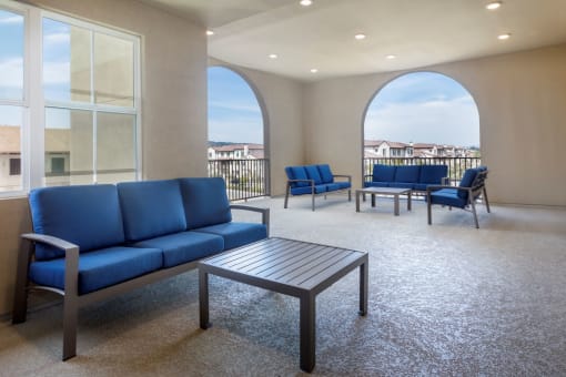 Springville Seniors Apartments Community outdoor covered balcony on the 2nd floor with blue outdoor furnishings and beautiful views of Camarillo
