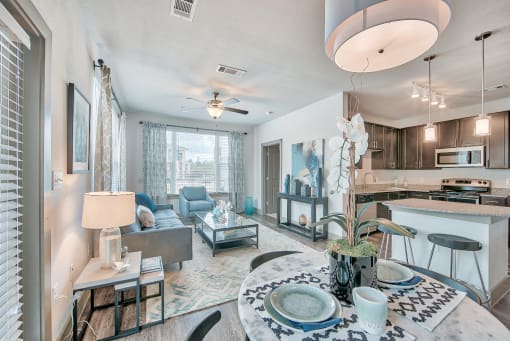 A spacious and modern living room with a dining area and kitchen in the background.