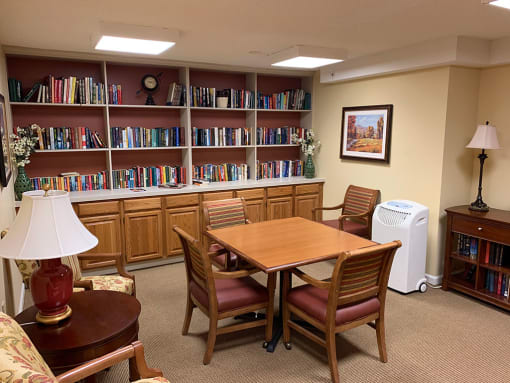 A library with a table, chairs, and bookshelves.