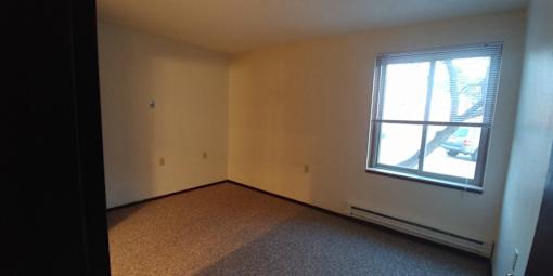 A room with a window and a car parked outside.
