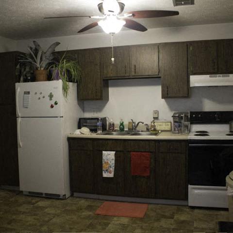 a kitchen with a white refrigerator freezer next to a stove top oven