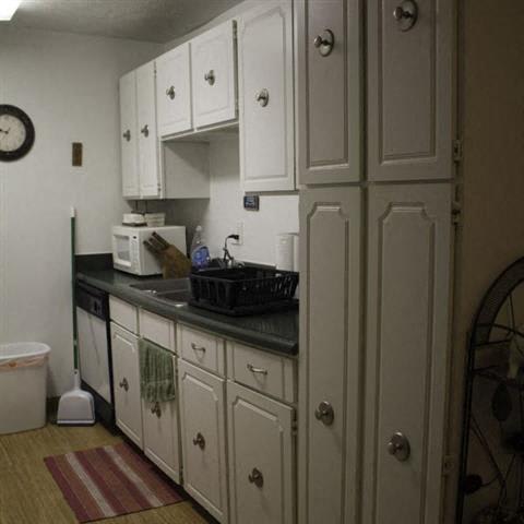 a kitchen with white cabinets and a black counter top