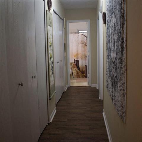 a hallway with a wooden floor and closets