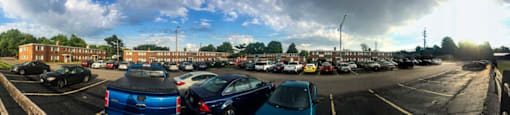 a parking lot full of cars and brick apartment buildings in the background