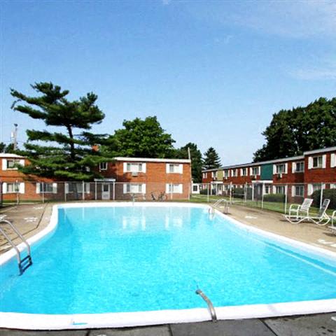 a large blue swimming pool in front of a brick apartment building