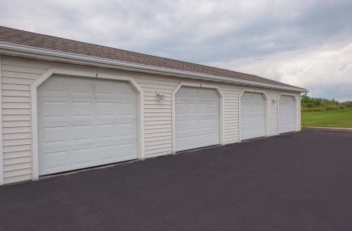 row of white vinyl garages with matching white garage doors at an apartment community, well-maintained exterior