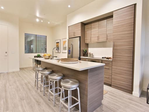Apartments in Old Town Scottsdale AZ - Dusk Scottsdale - Kitchen with Large Island, Barstools, Beige Cabinets, White Quartz Countertops, and Stainless Steel Appliances