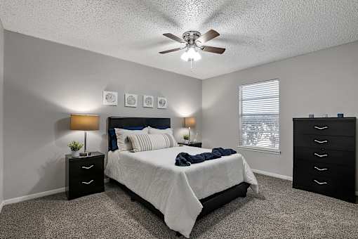 Bedroom with ceiling fan, carpet flooring, and window at Sage Creek Apartments