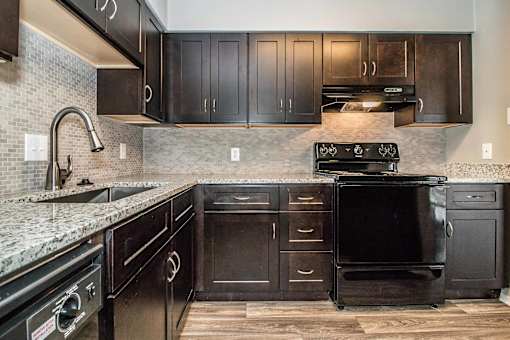 Kitchen with dark wood cabinets and stainless appliances at Verano Oaks Apartments