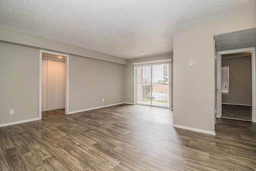 Spacious living room with neutral walls and wood-style flooring at Verano Oaks Apartments in Hurst, TX
