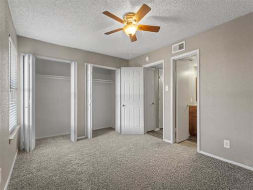 Bedroom with ceiling fan and large window at Verano Oaks Apartments