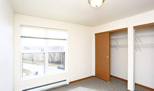A room with a brown door and a window with blinds.