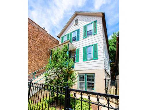 A house with green shutters and a black fence.