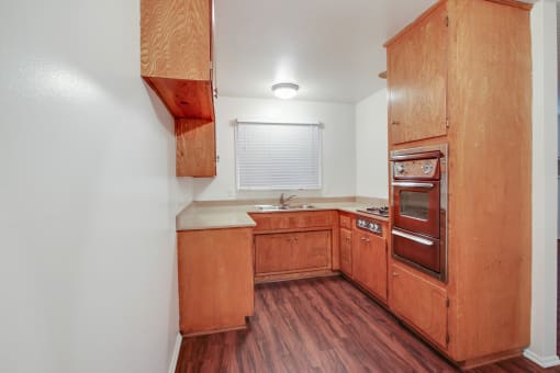 Kitchen with stainless steel Microwave oven,  gas cooktop, quartz countertops, wood kitchen cabinets, and wood-inspired flooring