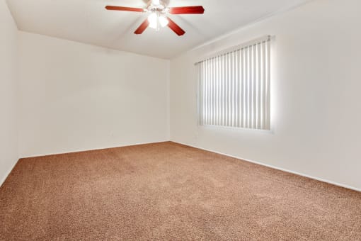 Bedroom with ceiling fan and carpeted floors, vertical window blinds on the right