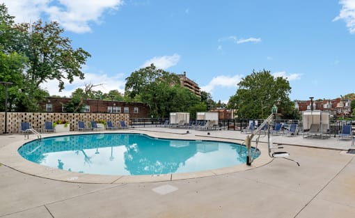 a swimming pool with chairs around it at an apartment complex