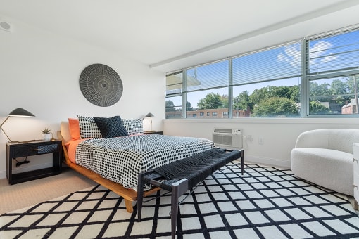 Large, carpeted bedroom with air conditioning unit and expansive wall to wall windows