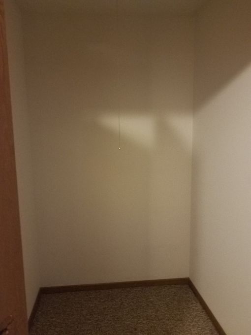 A hallway with a carpeted floor and white walls.