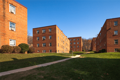 A row of red brick apartment buildings with green grass in front.
