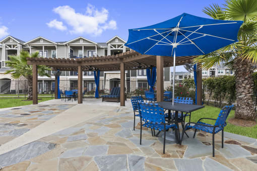Apartments for Rent New Braunfels - Canyon House Apts - Outdoor Seating Area With Table and Umbrella, Plus Wooden Canopy With Seating for Sun Bathing