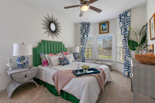 Two Bedroom Apartments in San Marcos, TX - Sadler House - Large Bedroom with Bay Style Windows, High Ceilings, Ceiling Fan, Plush Carpeting, and White Walls.