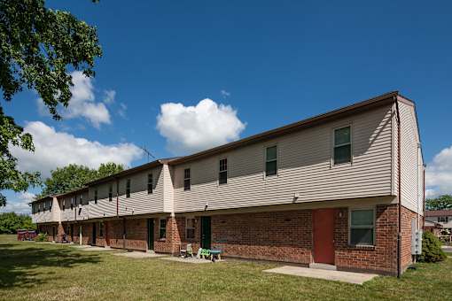 A long building with a red door sits in a grassy area.