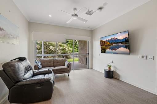A living room with a large TV on the wall and a couch.