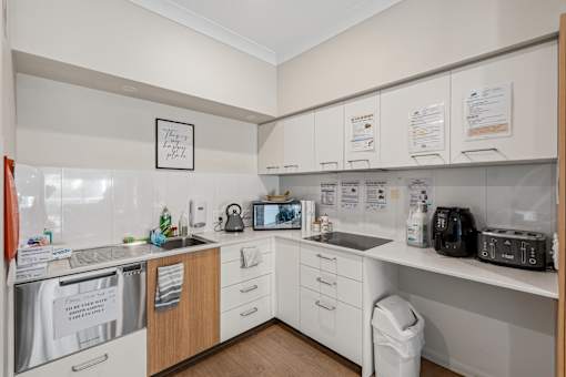 A small kitchen with white cabinets and a white fridge.