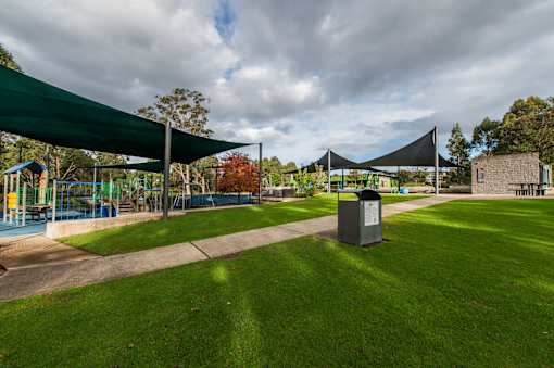 A park with a playground and a trash can.