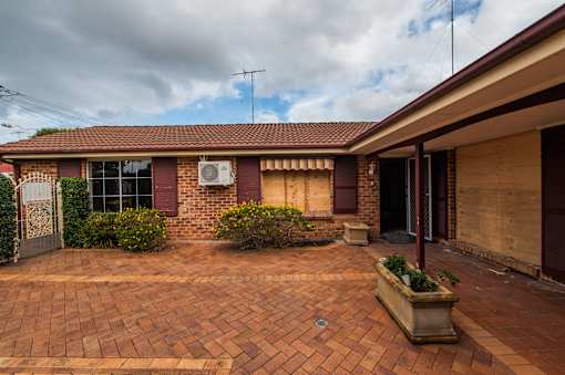 A house with a red brick driveway and a white air conditioning unit on the wall.