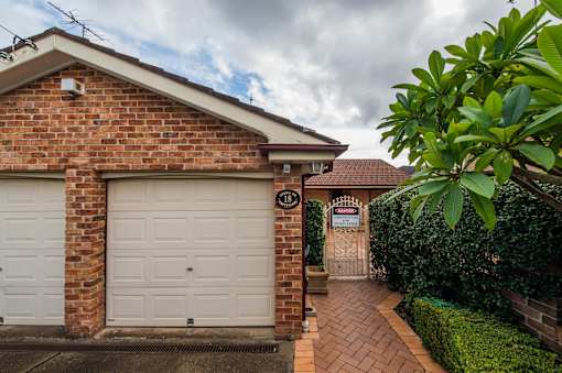 A brick house with a white garage door and a sign that says 151.