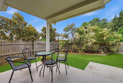A patio with a table and chairs under a roof.