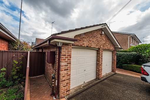 A house with a white garage door and a brown brick wall.