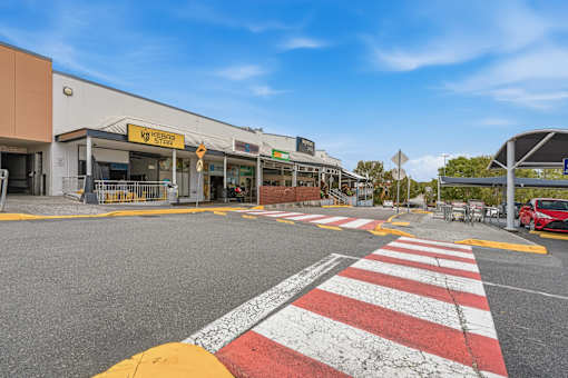 A red and white zebra crossing in front of a building with a yellow sign that says "KFC".