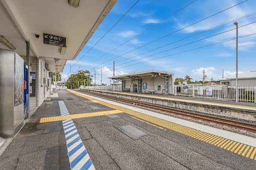 A train station platform with a blue and white striped safety line.