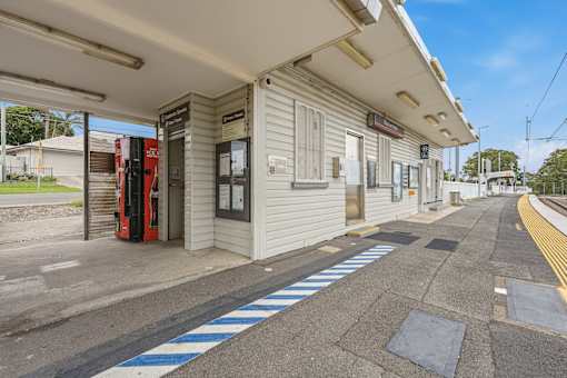 A train station platform with a red train on the left.