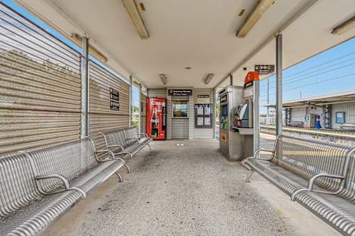 A bus stop with a red bus in the background.