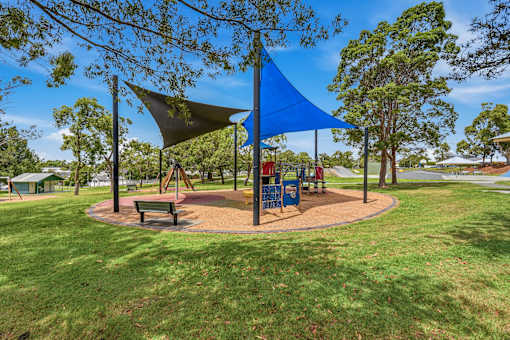 A playground with a blue shade structure and a green bench.