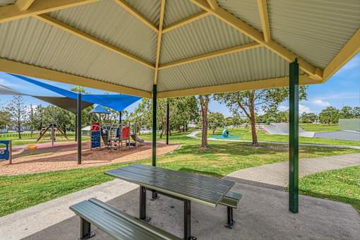 A park with a picnic table and playground equipment.