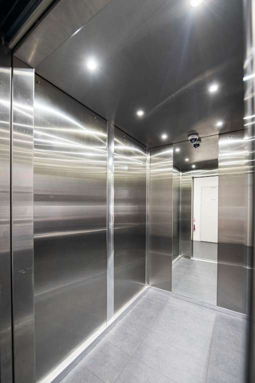 A long hallway with a metal wall and a door at the end.
