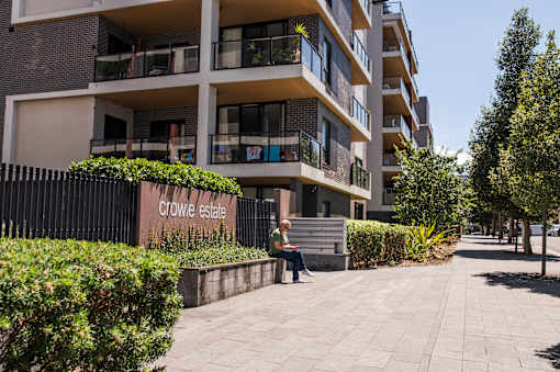 A woman is sitting on a bench in front of Crowie Estate.