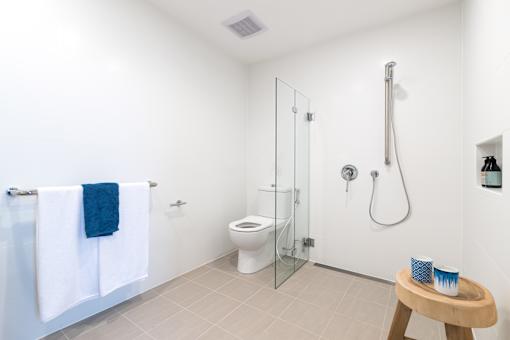 A white bathroom with a toilet, shower, and a towel.