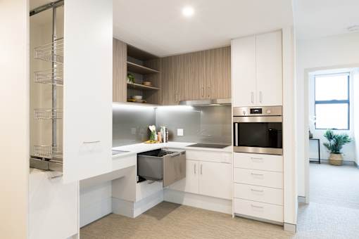 A modern kitchen with white cabinets and appliances.