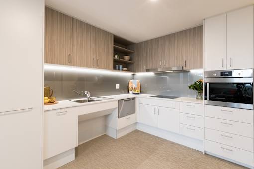 A modern kitchen with white cabinets and a wooden backsplash.