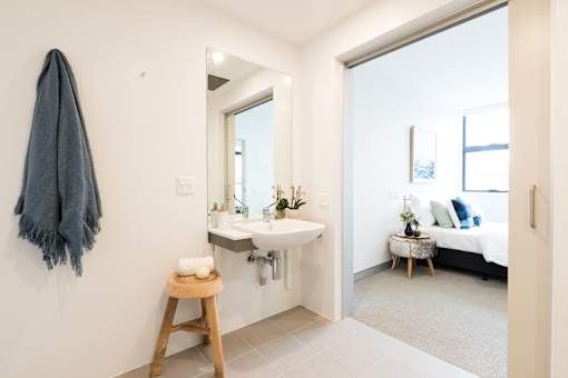 A bathroom with a towel hanging on the wall and a mirror above the sink.